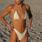Woman in a white bikini standing on a sandy beach.