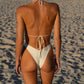 Woman in a white bikini standing on a sandy beach