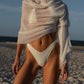 Woman in a white bikini and shawl on a beach