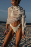 Woman in a white bikini and shawl on a beach