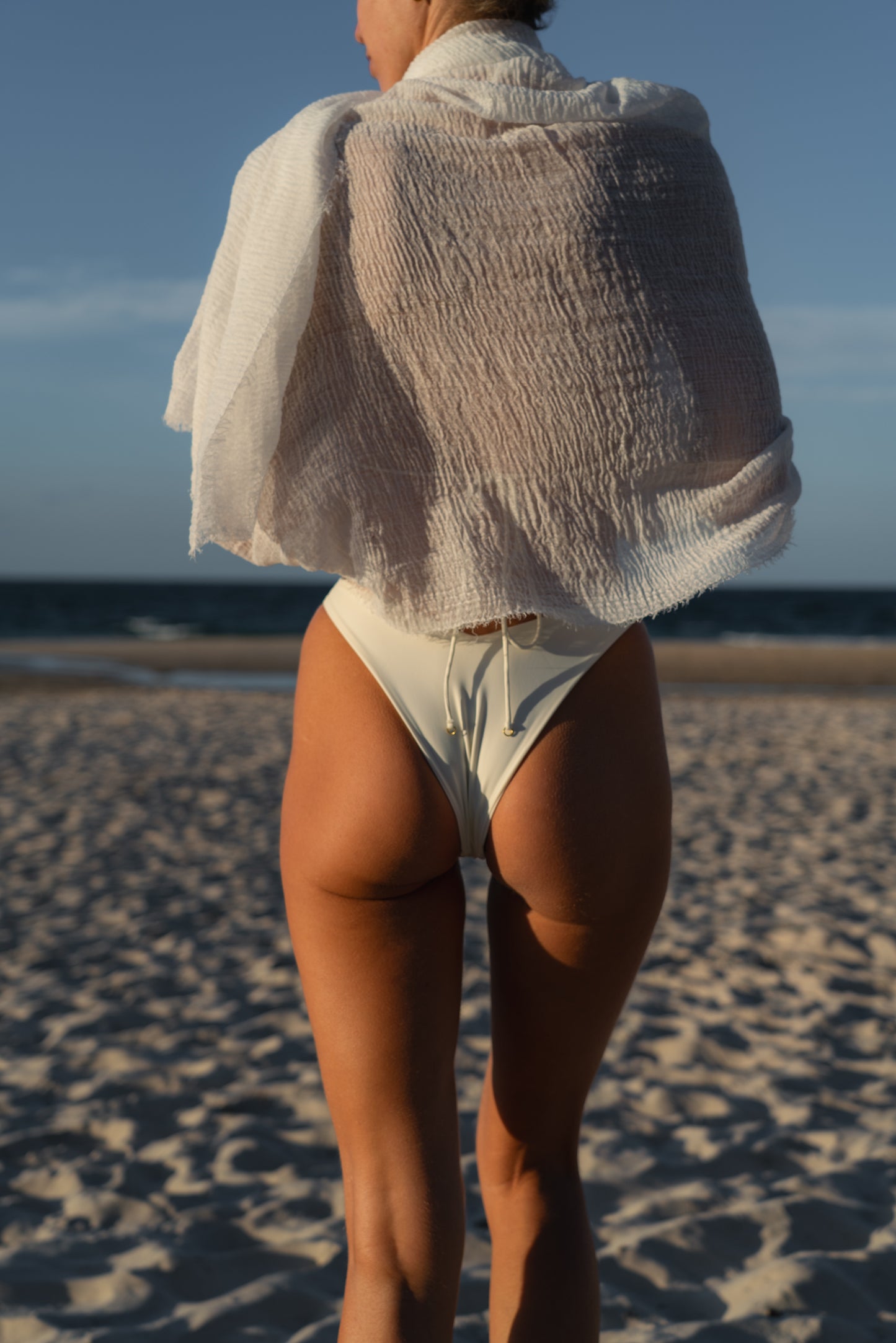 Person wearing a white bikini and cover-up on a beach