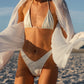 woman wearing a white bikini with a white cover-up on a beach